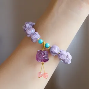 Detail of purple pumpkin-shaped beads and carved purple beast pendant on handmade bracelet