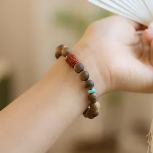Dettaglio del bracciale in legno di agar Kinam con ciondolo PiXiu e perla turchese