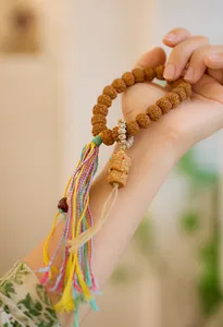 Detailopname van Rudraksha-armband met kleurrijke kwastjes en een houten Boeddha-hanger