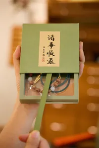 Detail van de matcha groene juwelendoos met kralenarmband en calligrafisch etiket