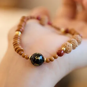 Detalle macro de pulsera de cuentas con cuenta negra grabada y semillas de bodhi