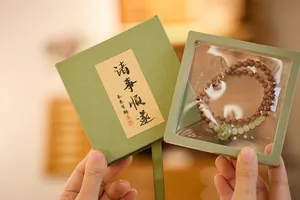 Detail van donkere houten kralen met groene jade bedel in een luxe geschenkverpakking