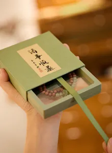 Detailopname van kralenarmband met houten en jade kralen in een groene geschenkdoos