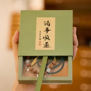 Handbeeld van een groene juwelendoos met een armband van houten en jade kralen binnenin