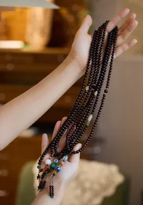 Macro detail of sandalwood Buddhist prayer beads with cloisonné charms and tassel accents