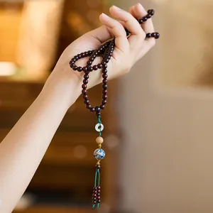 Detail of red sandalwood 108 beads with white jade and blue ceramic charm accents