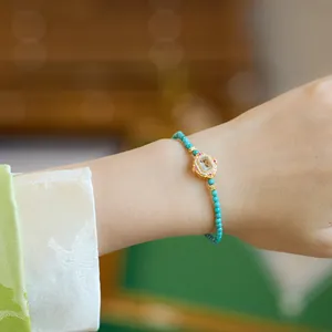 Macro-opname van de turquoise kralenarmband met blauwe edelsteen en gouden zetting