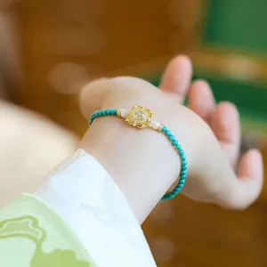 Detail van turquoise kralenarmband met zilveren smaragd en witte parel accenten