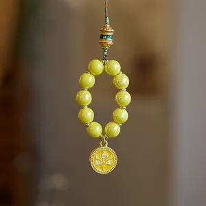 Ethnic yellow bead phone charm with golden prayer wheel and protective eye pendant