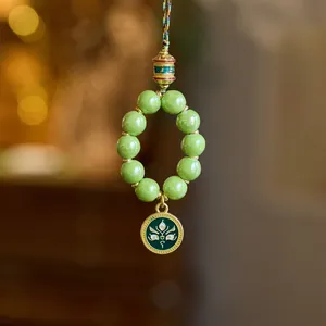 Close-up of green beads with ancient gold finish charm and divine eye pendant