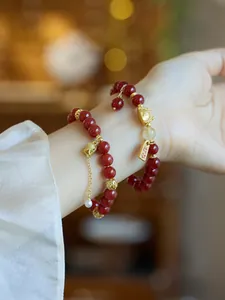 Détail du bracelet en agate rouge avec chat porte-bonheur et pendentifs dorés