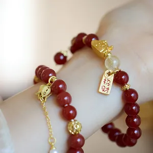 Détail du bracelet en agate rouge avec breloque chat et pendentif doré de fortune