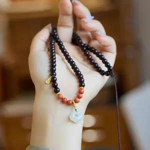 Red sandalwood bead necklace with white jade flower and gold gourd charm on hand