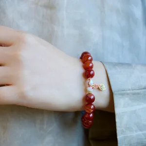 Gros plan d'un bracelet en agate dragon rouge avec un délicat pendentif queue de poisson