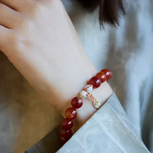Détail d'un bracelet en agate avec un pendentif en émail coloré en forme de queue de poisson