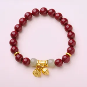 Vue détaillée du bracelet en perles de cinabre avec pendentifs lotus et accents de jade