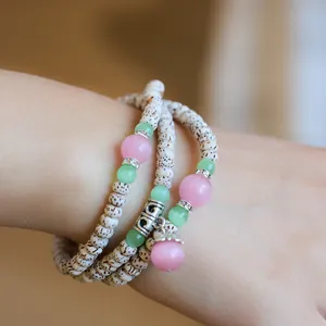 Close-up of Xingyue Bodhi wrap bracelet with cat eye stones and metallic Ruyi charm