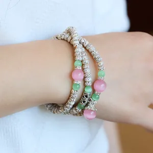 Close-up of Bodhi seed bracelet with cat-eye stones and silver beads on a wrist