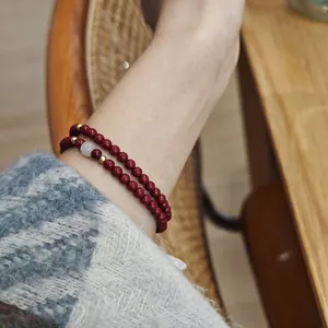 Détail du bracelet en cinabre rouge avec espaceurs en argent et perle de jade blanc