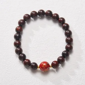 Close-up of red cinnabar bead and dark wood sandalwood prayer beads with golden accents