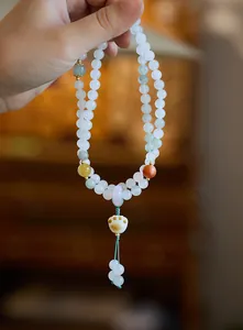 Dettaglio del bracciale di perle in pietra naturale con ciondolo a zampa di gatto bianco