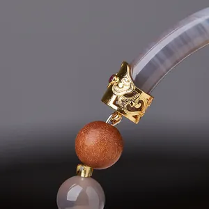 Macro detail of sandalwood beads and grey agate with golden metal floral sleeve