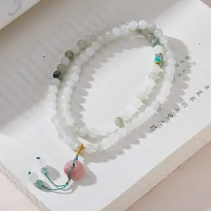 Dettaglio bracciale di perle di giada con ciondolo a ciambella rosa e nodo in seta verde