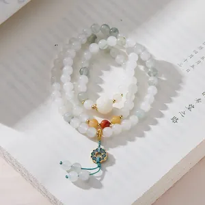 Dettaglio del bracciale multistrato in giadeite con ciondolo a loto smaltato su libro