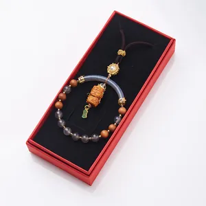 Detailed view of carved sandalwood Buddhist pendant with gray agate in red gift box