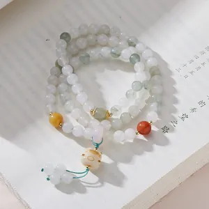 Dettaglio del bracciale di perle di giada a più strati con ciondolo a gatto e nappa