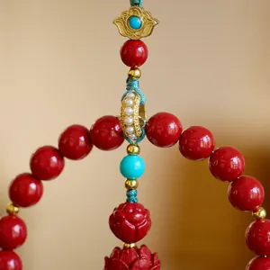 Close-up of red cinnabar beads with gold-tone hardware and carved lotus flower pendant