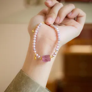 Natural purple pearl bracelet with carved jade cylinder and golden heart charm on wrist