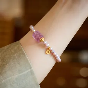 Natural purple freshwater pearl bracelet with gold coin charm on female wrist
