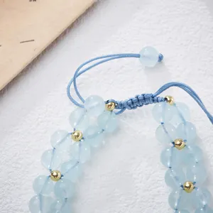 Détail du bracelet en aigue-marine avec perles dorées et cordon tressé ajustable bleu