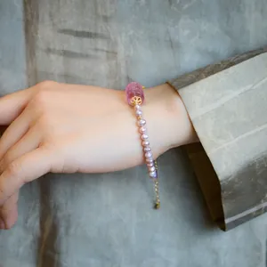 Detail of purple freshwater pearl bracelet with carved gemstone and golden floral spacers