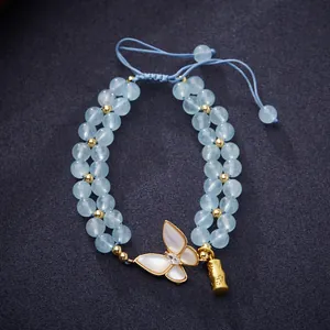 Détail du bracelet en perles d'aigue-marine avec pendentif papillon et décor bambou
