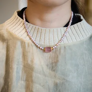Elegant purple freshwater pearl necklace with a pink carved stone pendant on a model