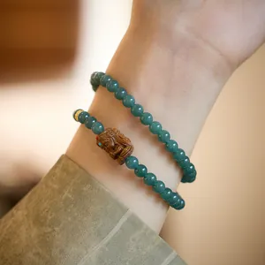 Gros plan d'un bracelet double boucle en jade vert avec un pendentif Pixiu sculpté