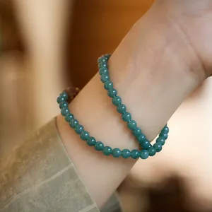 Vue détaillée du bracelet double rang en jade bleu avec perles en bois sur le poignet