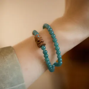 Bracelet double tour en perles de jade vert avec un pendentif en bois sculpté