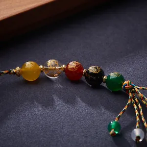 Detailed macro view of Five-color Agate beads with gold Buddhist carvings and woven cord