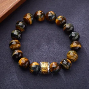 Natural yellow and blue tiger eye stone bracelet with golden engraved bead on purple fabric