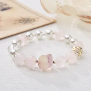 Handmade rose quartz bracelet with white pearls and fluorite stone on vintage background
