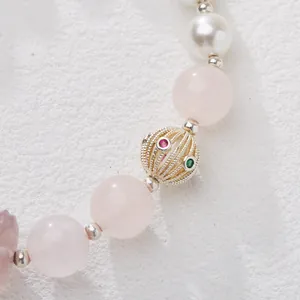 Close-up of pink quartz beads and pearl bracelet with golden hollow gemstone charm