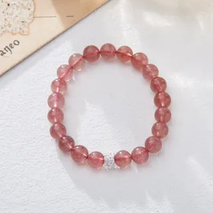 Macro shot of natural pink strawberry quartz beads and sparkling silver charm on white base