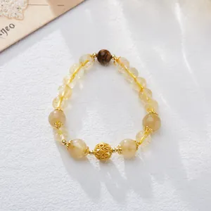 Macro shot of Citrine beaded bracelet with Tiger Eye stone and golden filigree charms