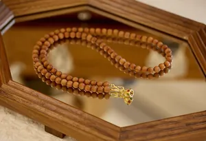 Détail du collier en perles de bois avec breloque cloche dorée et gemmes colorées