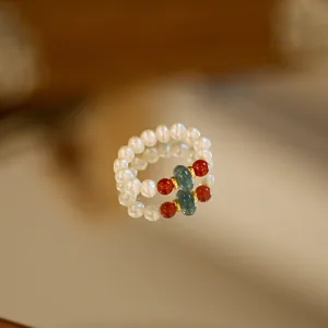 Detailed close-up of natural pearl and emerald jade ring with golden spacers and reflection