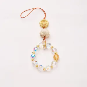 Détail du pendentif lotus avec perles irisées et cordon tressé pour sac ou mobile
