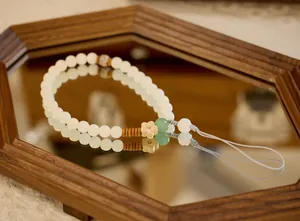 Detail view of handcrafted white bodhi root phone strap with green aventurine flower charm
